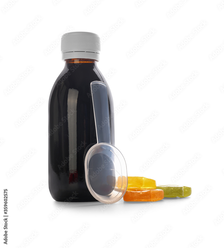 Bottle of cough syrup with candies on white background