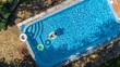 © Iuliia Sokolovska - Aerial view of beautiful girl in swimming pool from above, swim on inflatable ring donut and has fun in water on family vacation on tropical holiday resort