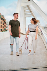 beautiful curvy model and handsome man taking a walk with their dog in an urban scene