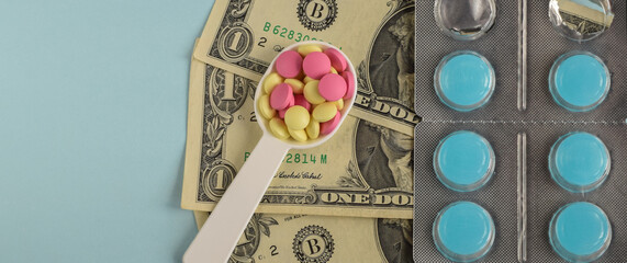 Colored pills in a medical spoon on a background of american dollars. Economic crisis. The cost of treatment. Selective focus. Copy space.