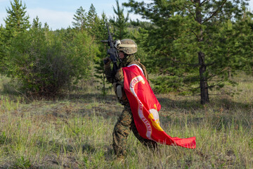 Fully armed american soldier with US Marine Corps flag in the summer forest, active military game airsoft.