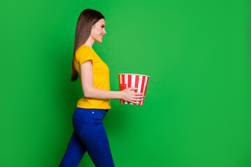 Poster - Profile side view portrait of her she nice attractive pretty cheery straight-haired girl holding in hands carrying sweet caramel corn box isolated on bright vivid shine vibrant green color background