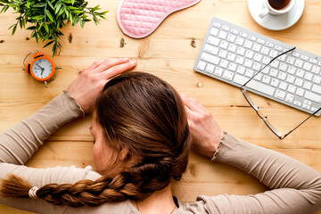 Overworked woman sleeps on wooden office desk top view