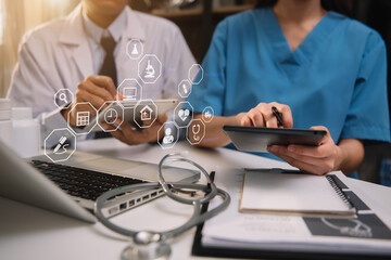 Doctors working together on laptop computer and tablet and medical stethoscope on clipboard on desk, electronics medical record system EMRs concept.
