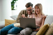 © JustLife - Young couple watching movie on lap top. Loving couple enjoying at home.