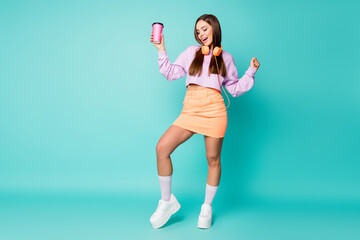 Sticker - Full body photo of attractive lady hold coffee mug listen modern technology earphones dance tender moves wear violet sweater orange skirt shoes socks isolated teal color background