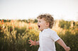 adorable blond toddler baby boy running through the summer road and field