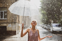 Happy Woman Walking Under Summer Rain. Outdoor Portrait Of Young Beautiful Smiling Lady Holding Transparent Umbrella, Posing In Street Of European City. Copy, Empty Space For Text