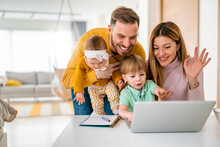 Happy Family At Home Using Computer, Waving While In A Live Video Chat