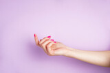 Fototapeta Kwiaty - Beautiful hand of a young woman on a purple background. Beautiful manicure with space for text.
