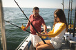 © Wavebreak Media - A Caucasian man and his teenage daughter holding fishing rods and talking