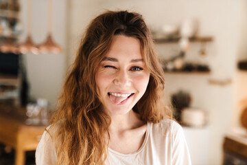 Sticker - Cheerful lovely girl grimacing while standing in the kitchen