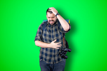 Wall Mural - Portrait of a puzzled bearded traveler man holding hands on his head isolated over chroma background