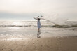 © Milou Dirks - Portrait of woman in white dress standing in the ocean holding white plastic drape in the wind in teh evening light at sunset
