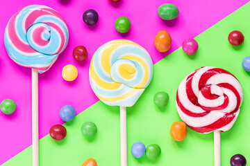 Creative flat lay overhead view composition with colorful sweet lollipops on bright two tone background. Children party concept. Festive background.