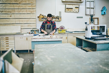 Wall Mural - serious skilled owner of manufacturing business spending time in his workshop with equipments and to