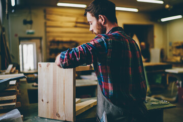 Wall Mural - serious caucasian male owner of manufacture repainting furniture by himself in workshop with profess