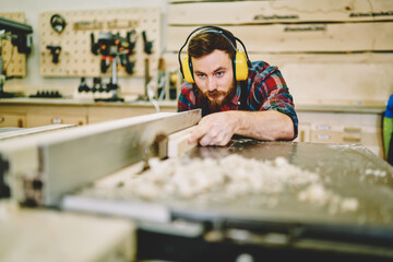 Wall Mural - skilled male in protection equipment for safety during woodwork with circular making details for con