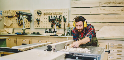 Wall Mural - self employed craftsman concentrated on carpentry work using circular for wooden plank, skilled male