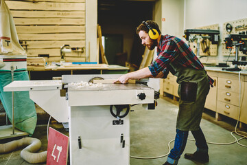 Wall Mural - young craftsman concentrated on carpentry work with wooden using circular for saw plank, skilled mal