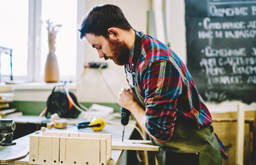 Wall Mural - caucasian guy spending time in garage on diy using tools for hobby making furniture by himself, prof