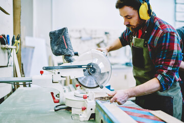 Wall Mural - serious caucasian male worker concentrated during work with circular in workshop, skilled foreman in