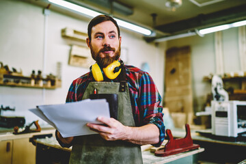 Wall Mural - handsome bearded male owner of crafts business looking away thinking about improvement of workshop, 