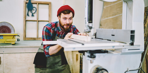 Wall Mural - smiling hipster guy satisfied with carpentry courses and learning how to use electric machinery for 