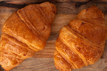 Fresh croissants on wooden board close up