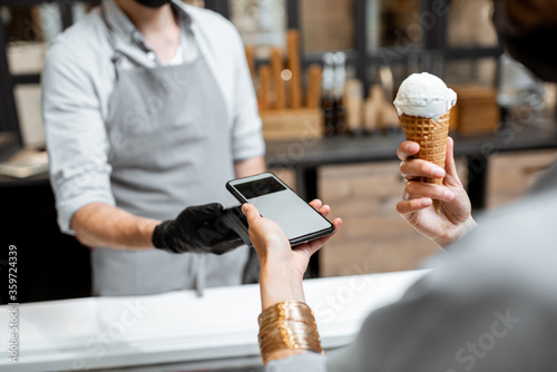 Cuadros en Lienzo Seller in makes contactless payment for a client in the ice cream shop, close-up