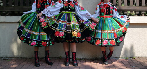 Three girls in traditional folk costumes from Lowicz in Poland in street while join Corpus Christi celebration