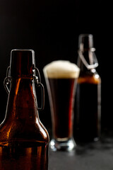 Dark crafted beer in glass and bottle on black background