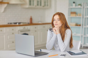 Beautiful red haired girl with laptop computer at home. Online work, business, education or communication