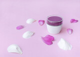 Fototapeta Tulipany - ..Cosmetic cream container and pink and white flower petals on a pink background. Peony flowers and white face cream. side view