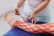 © dsheremeta - Female doctor helps woman by putting kinesio tape on her leg. Young caucasian girl with kinesiology elastic therapeutic tape on her leg