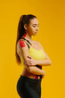 © dsheremeta - Young caucasian girl with kinesiology tape on her belly and leg, on yellow background. Sport and rehabilitation, kinesiotherapy treatment.