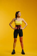 © dsheremeta - Young caucasian girl with kinesiology tape on her belly and leg, on yellow background. Sport and rehabilitation, kinesiotherapy treatment.