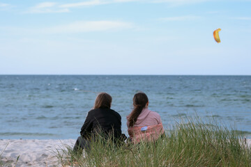 two girls sitting in a sand dune on the beach