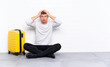 © luismolinero - Young handsome man sitting on the floor with a suitcase with surprise facial expression