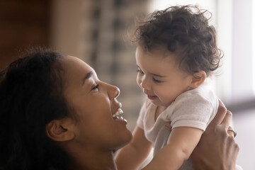 Wall Mural - close up smiling beautiful african american woman holding adorable little daughter, enjoying tender 