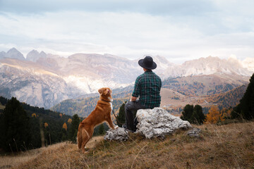 man with a dog in the mountains. travel, hiking with a pet. nova scotia duck tolling retriever