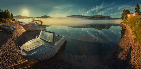 Wall Mural - sea tourism. foggy morning on the lake, bright sun, ship and boat in backlight near the shore.