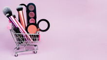 Eye Shadow Blush, Lipstick And Various Makeup Brushes In A Pink Trolley Of The Buyer. The Concept Of Online Shopping Decorative Cosmetics, Discounts In Stores
