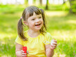 © Ermolaev Alexandr - Laughing girl with syndrome down blows bubbles in a summer park