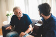 © chokniti - An adult hipster son and senior father at home, playing guitar and enjoy with music
