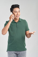 Wall Mural - Cheerful casual man talking on phone and celebrating standing on white studio background