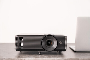 Modern video projector and laptop on table against white background