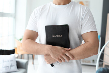 Wall Mural - Young man with Bible at home, closeup