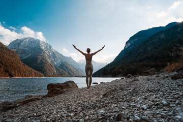 Wall Mural - Young woman is practicing yoga at mountain lake.