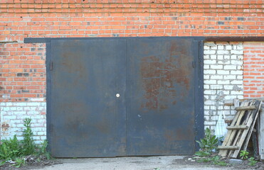 Wall Mural - A large metal door in the wall of their red and white bricks